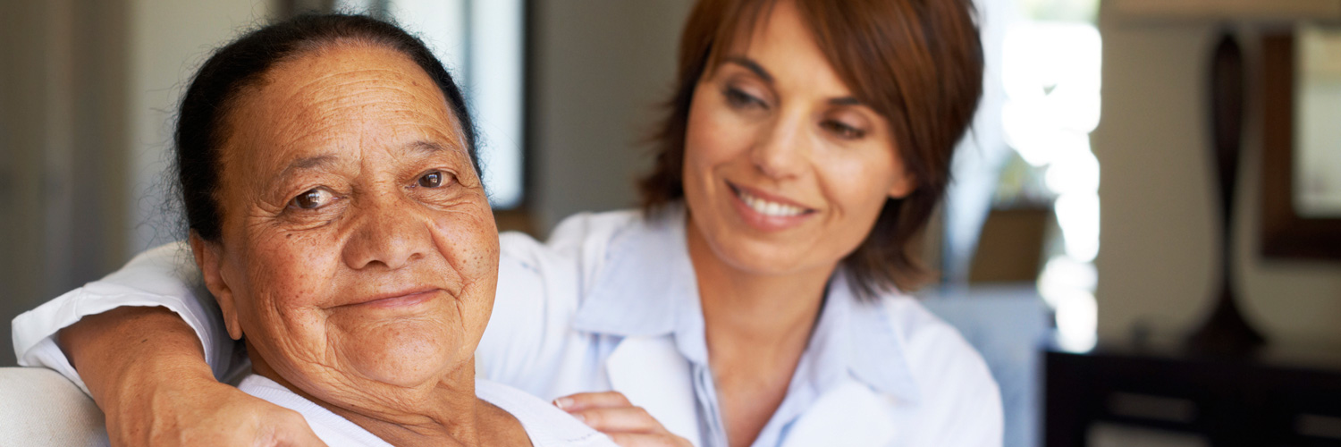 caregiver and elderly woman smiling at the camera